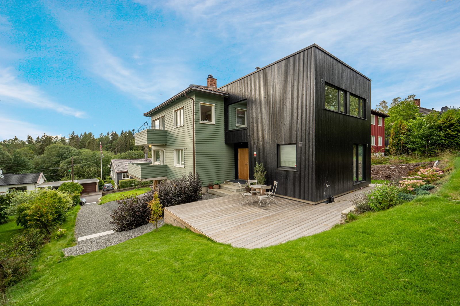 Svart tilbygg på eldre grønt hus